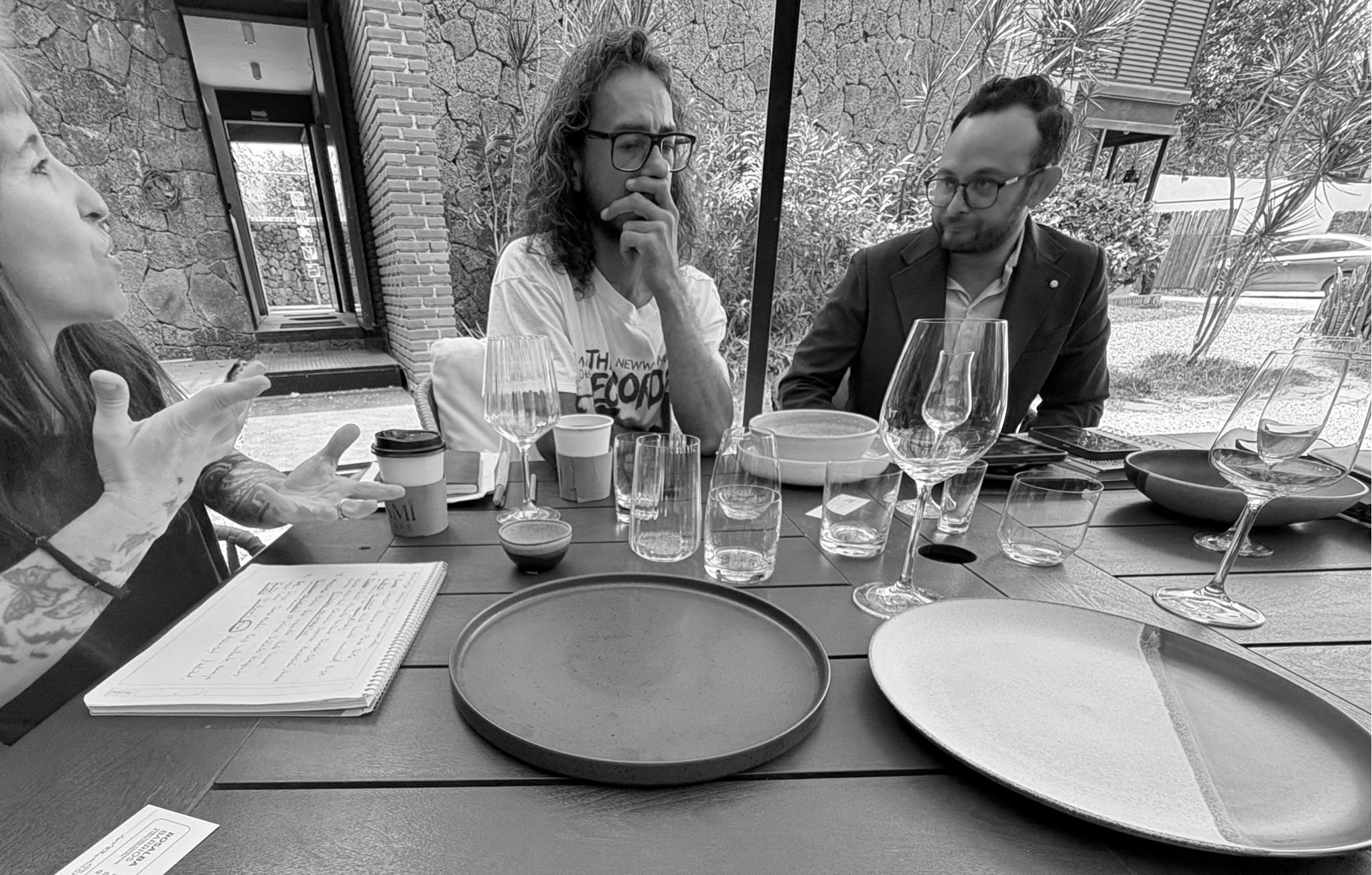 Collaborators in discussion around a table with notebooks and ceramic plates