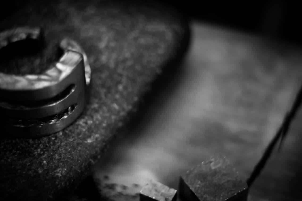Close detail of a silver piece held against a worked metal surface